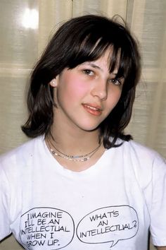 a young woman wearing a white t - shirt with words on it