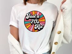 Step back in time with this "Just a 70's Kid" T-Shirt, the perfect way to relive the vibrant and funky era of the 1970s! This retro 70's tee features a bold and nostalgic design that embodies the spirit of disco, peace, and groovy vibes. Whether you're a fan of vintage 70's fashion or simply want to show off your love for the era, this 70's lover tee brings the past to life with a modern twist. The soft and comfortable fabric makes it ideal for casual wear, 70's-themed parties, or as a thoughtfu Cheap Retro Rainbow T-shirt, 70s Retro Style, Groovy Fashion, 70s Vintage Fashion, 70s Shirts, 70s Vibes, Faith Shirt, 70s Retro, 70s Fashion