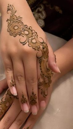 two hands with henna tattoos on them and one holding the other's hand