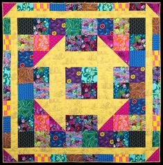 a yellow and blue quilt with colorful flowers on the center, surrounded by multicolored squares