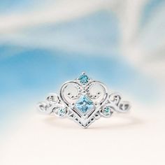 a white gold ring with an aqua blue topazte and diamond heart in the center