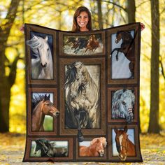 a woman holding up a blanket with horses on it in front of trees and leaves