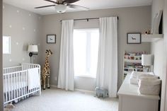 a baby's room with a white crib and a giraffe in the window