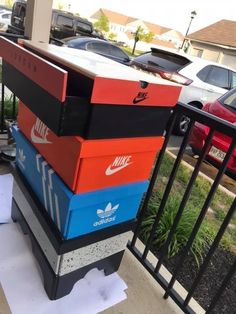 several nike boxes stacked on top of each other in front of a black metal fence