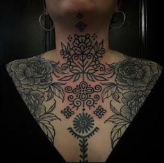 the back of a woman's neck is shown with tattoos and flowers on it