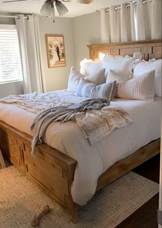 a bed with white sheets and pillows in a bedroom