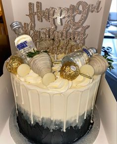 a birthday cake with white frosting and silver decorations on top is decorated with liquor bottles