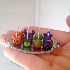 a person holding a small tray with little toy animals on it's sides and candles in the middle