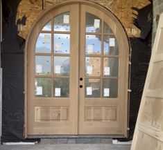 a large wooden door sitting next to a tall building with windows on it's side