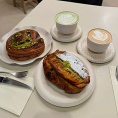 there are three different types of pastries on the table next to two cups of coffee