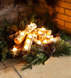 a bunch of candles that are sitting in the middle of a pile of logs and pine cones