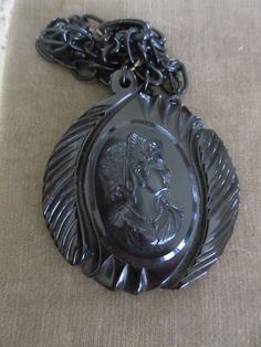 Vintage circa 1930 black celluloid cameo necklace. This vintage 2.5'' black gothic necklace features a large celluloid cameo on a 22'' celluloid link chain. The chain has a hook closure that closes in the front. This estate find is large and wonderful. It wears with a bold style. The cameo has beautiful features and it is beautifully framed on it's carved backdrop. Lovely vintage condition. Vintage Black Medallion Jewelry, Victorian Black Medallion Jewelry, Black Victorian Medallion Jewelry, Vintage Black Medallion Necklace, Vintage Black Cameo Jewelry, Vintage Black Cameo Necklace, Black Cameo Necklace In Vintage Style, Black Cameo Jewelry For Collectors, Black Cameo Medallion Jewelry