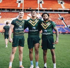 three rugby players are posing for a photo in front of an orange stadium bleachers