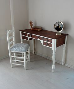 a wooden desk with two chairs and a mirror on the wall next to it in a room