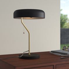 a desk lamp sitting on top of a wooden table next to a laptop and pen