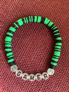 Celebrate gaming with our Gamer bracelet. Black and green clay polymer beads with glow in the dark resin beads spelling out Gamer. Measured to standard adult sizing, if different sizing, colors, or quantity are needed please reach out.  Bracelet will arrive in organza bag with two vinyl stickers that are perfect for your sticker collection, water bottle, or laptop. Note: not intended for children under 3 as beads may be a choking hazard.  Do not expose bracelet to water, chemicals, or perfume. Bead Business, Glow In The Dark Resin, Polymer Beads, Clay Polymer, Green Clay, Bracelet Black, Resin Beads, Sticker Collection, Organza Bags