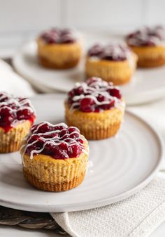 small desserts are sitting on white plates with drizzled cranberry sauce