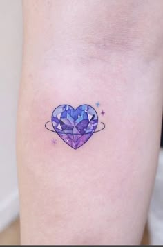 a small heart tattoo on the right side of the leg, with stars around it