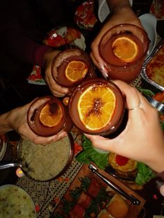 several people are holding orange slices in their hands and serving them with soup or pudding