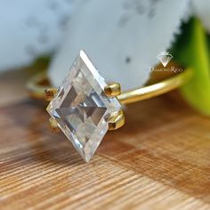 a close up of a ring on a wooden surface with flowers in the back ground