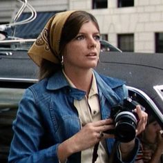 a woman holding a camera in front of a car