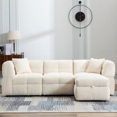 a living room with a sectional couch and large clock on the wall in the background