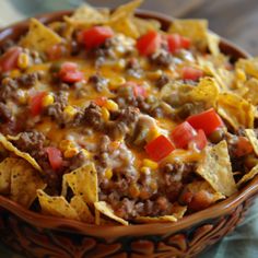 a bowl filled with chili cheese and tortilla chips on top of a table