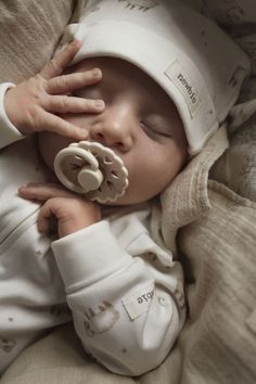 a newborn baby is wearing a white hat and holding a pacifier in it's mouth