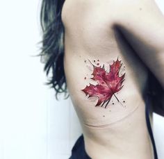 a leaf tattoo on the side of a woman's stomach, with red ink