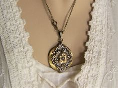 "A brushed bronze round locket is adorned with a garland of tiny roses and flourishes of leaves around it's perimeter. A six petal flower is placed in the center of the front. A ribbed bail holds the locket on a 20\" bronze cable link chain closed with a lobster clasp. The chain in enhanced with a small scrolling connector near the bail. The reverse side of the locket is plain brushed finish with a soft glow. If you prefer a different length chain, please let me know. This 32mm (1 1/4\") round l Antique Brass Locket Necklace For Wedding, Bronze Brass Locket Necklace For Wedding, Antique Finish Brass Locket Necklace For Wedding, Adjustable Antique Finish Wedding Jewelry, Antique Finish Adjustable Wedding Jewelry, Bronze Locket Necklace With Vintage Charm For Wedding, Bronze Vintage Charm Jewelry For Wedding, Elegant Bronze Locket Necklace For Wedding, Bronze Antique Finish Jewelry For Wedding