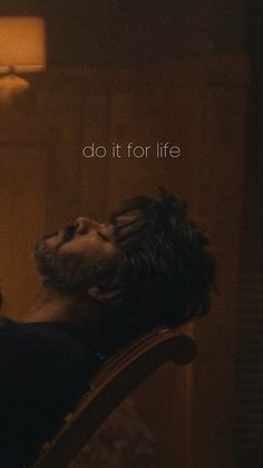 a man laying on top of a chair next to a wall with the words do it for life