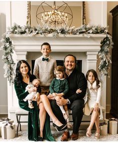 a family sitting in front of a fireplace with christmas decorations on the mantel and mantle