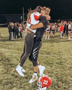 two girls hugging each other on a football field