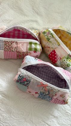 three small zippered bags sitting on top of a white bed next to each other