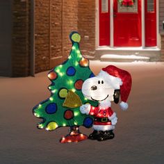 a snoopy christmas tree with lights on it and a dog figurine next to it