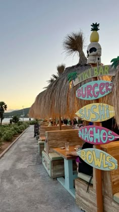 a row of tiki huts with signs on them