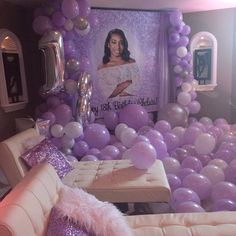 a room filled with balloons and couches covered in white and purple decorations, including a photo of a woman on the wall