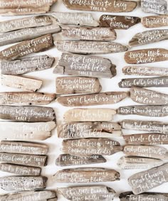 a bunch of driftwood with writing on them sitting next to each other in front of a white wall