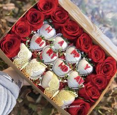 a box filled with lots of red and white heart shaped cakes next to flowers on the ground