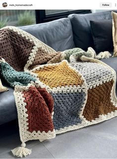 a crocheted blanket sitting on top of a couch next to pillows and blankets