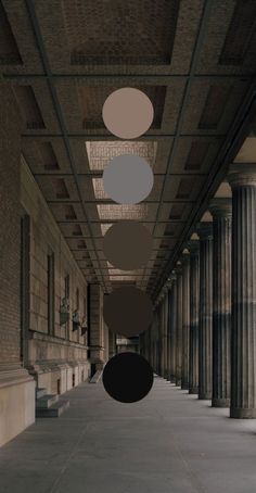 an empty hallway with columns and round shapes hanging from it's ceiling in the center