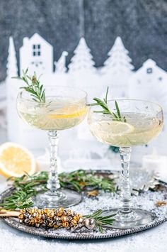 two glasses filled with lemonade and rosemary garnish sit on a silver tray