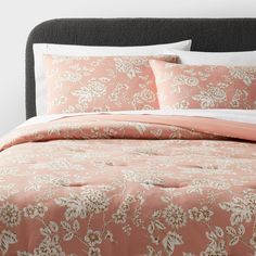 a bed with pink and white comforters on top of it