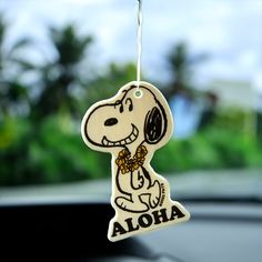 a wooden ornament hanging from the dashboard of a car with a cartoon character on it