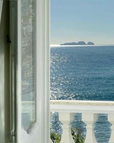 an open window looking out at the ocean and land in the distance from a balcony