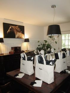 several white bags sitting on top of a wooden table in front of a painting and lamp