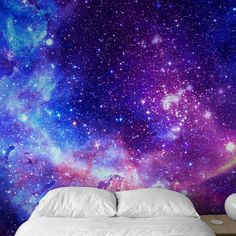 a bed sitting under a purple and blue galaxy wallpaper