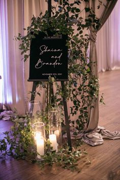 a sign with candles and greenery on it