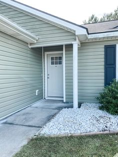 a house with a white door and blue shutters on the front entrance to it