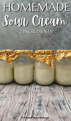 four jars filled with homemade sour cream sitting on top of a wooden table next to each other